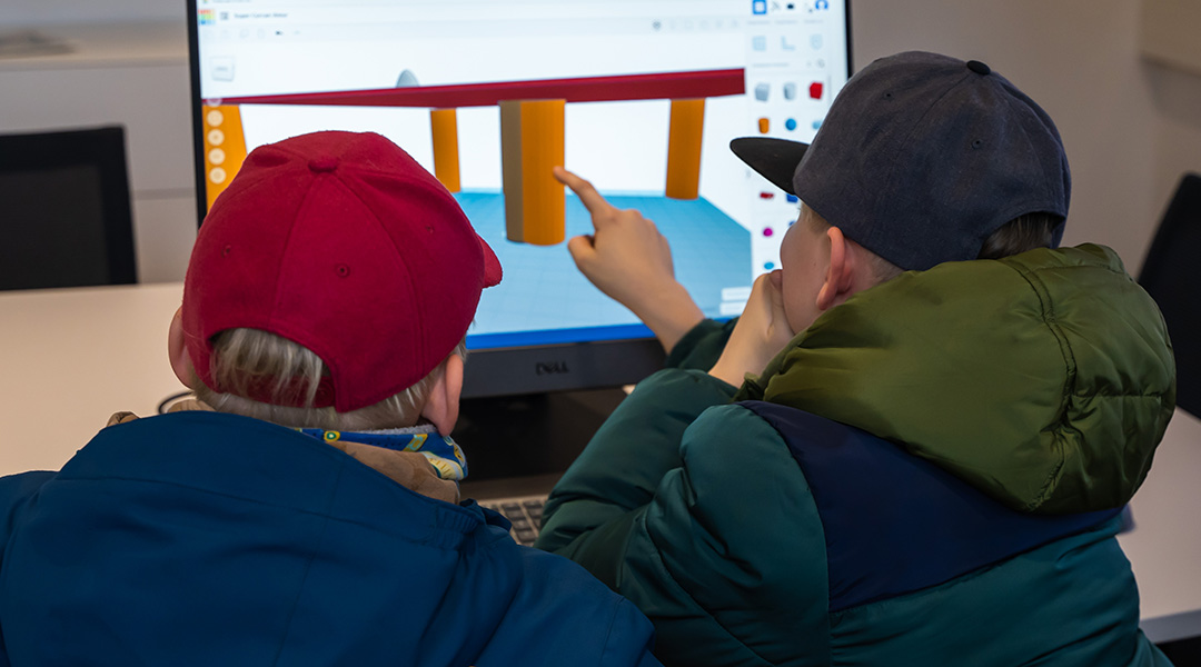 Zwei Jungen sitzen im BayernLab Forchheim vor einem Computer und probieren 3D-Konstruktion aus.